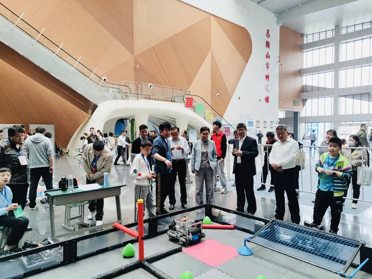 参赛学员在机器人赛事场地旁交流